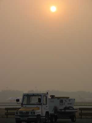 北京空港の搭乗用バス外から見た、場内作業車（トーイングカー？）と大陸の淡い夕景