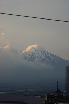 東京発の新幹線車窓からみた、頂上に雲がかかり夕陽を受ける富士山
