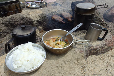 早期撤収による食材整理のため、白飯と色々煮とトンテキという豪華な朝食が置かれた、滋賀県南部・湖南アルプス野営地の竈辺