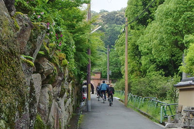 京都市街東部・南禅寺境内から琵琶湖疏水のインクラインを潜るトンネル「ねじりまんぽ」向こうの旧東海道跡（三条通）へ自転車で向かう平会一行