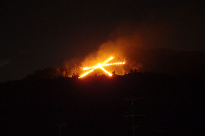 京都市街東部の神楽岡から見た、炎が盛りとなり大いに煙も生じる、京都・五山送り火「大文字」