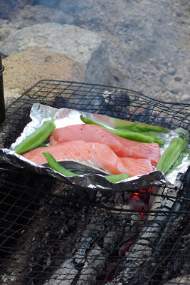 秋らしい生鮭を使ったホイル焼きの酒肴（しゅこう）と、その横に添えられた筆者自宅菜園産のオクラや唐辛子。2016年秋季野営会の一景