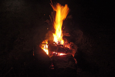 地面に石を組んで作られた炉で火柱を上げるキャンプファイヤー