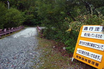 出水や老朽化で劣化したとみられる新穂高左俣林道の「通行自己責任橋」とその注意標示