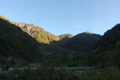 橋により左俣谷の東岸へと渡る林道と朝日を浴びる標高2500m超の稜線