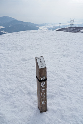 雪原に立つ赤坂山山頂標識と、麓彼方に覗く湖西平野北部及び琵琶湖