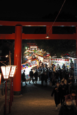 オミクロン・コロナの流行にもかかわらず参拝者で賑わう京都・吉田神社鳥居と犇めく節分祭の露店。2022年2月3日撮影