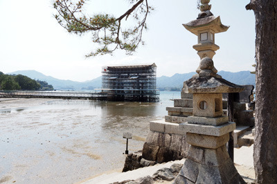 厳島神社前の石灯籠やその先の干潟上に聳える修復中の大鳥居
