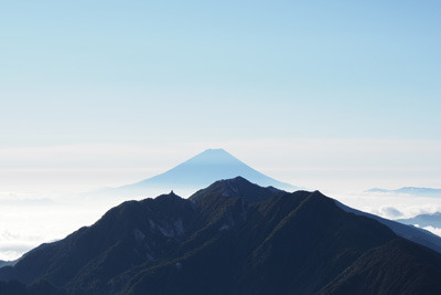 甲斐駒ヶ岳山頂からみた、朝日に輝く鳳凰三山越しの富士山
