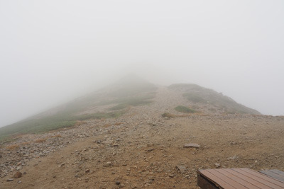 薬師岳山荘前のベンチから見た荒天で霞む薬師岳山頂方面